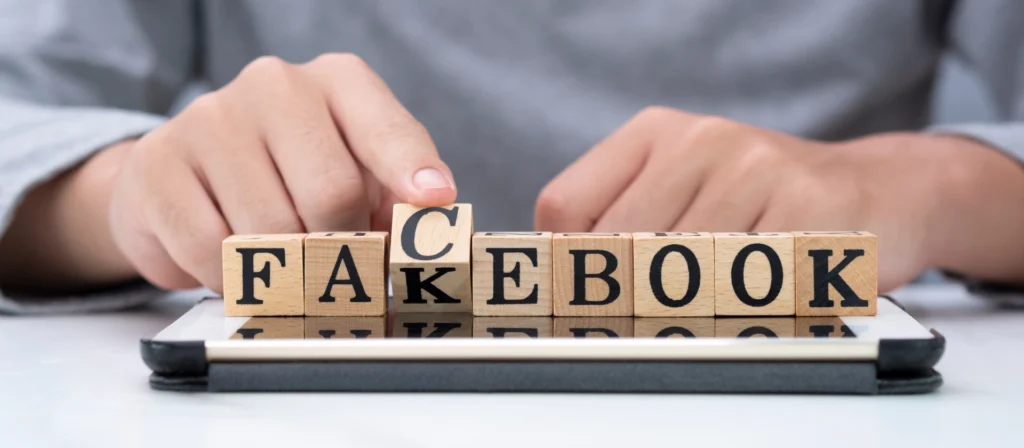 Hand kippt Holz woording für den Wechsel „Fakebook“ zu „Facebook“ auf Tablet