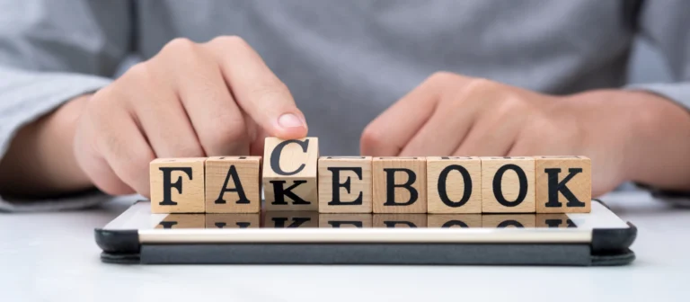 Hand kippt Holz woording für den Wechsel „Fakebook“ zu „Facebook“ auf Tablet