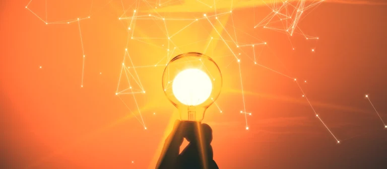 Hand hält eine Glühbirne. Durch die Glühbirne scheint die Sonne. Hintergrund Vernetzungslinien.