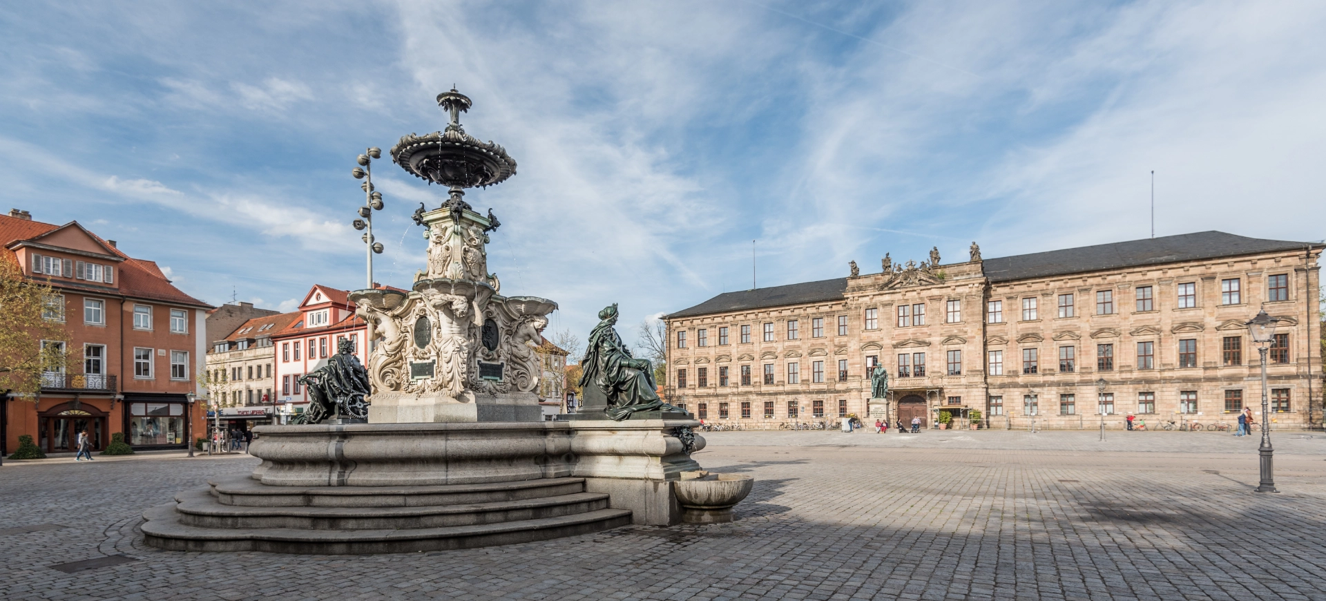Prunkvoller Brunnen vor barockem Schloss auf historischem Platz