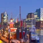 Hamburger Hafen mit Elbphilharmonie und beleuchteten Schiffen bei Dämmerung