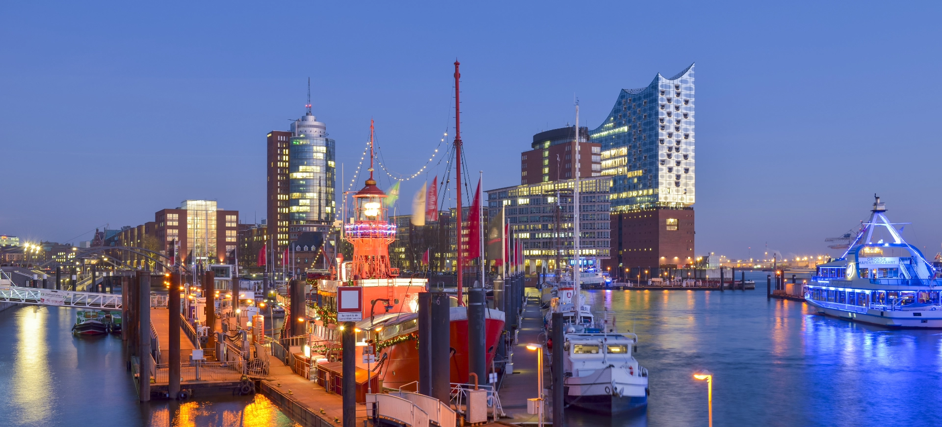 Hamburger Hafen mit Elbphilharmonie und beleuchteten Schiffen bei Dämmerung